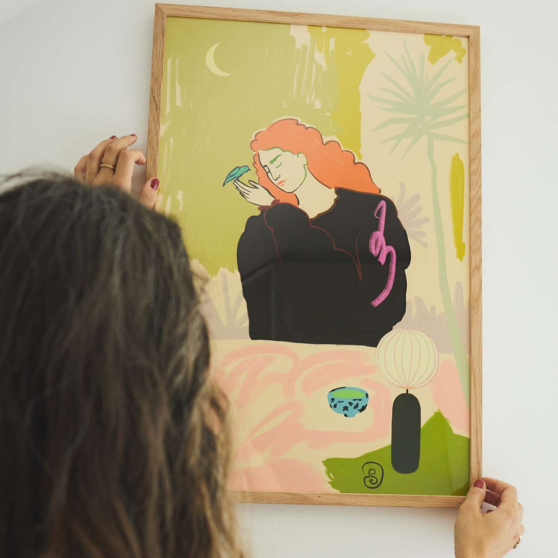 Person hanging a framed artwork on a wall